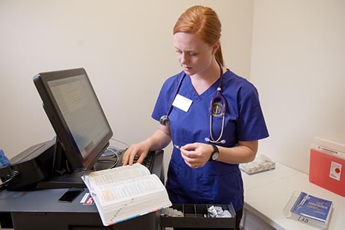 a nurse standing next to a computer